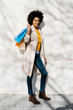 © Westend61 - Portrait of smiling woman with shopping bags standing at a wall