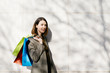 © Westend61 - Portrait of smiling woman with shopping bags standing at a wall