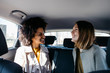 © Westend61 - Two happy women sitting in back seat of a car