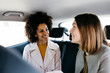 © Westend61 - Two happy women sitting in back seat of a car