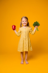 baby girl with eco bag and vegetables. baby girl blonde holding eco bag with vegetables on yellow background isolate, space for text, concept organic food