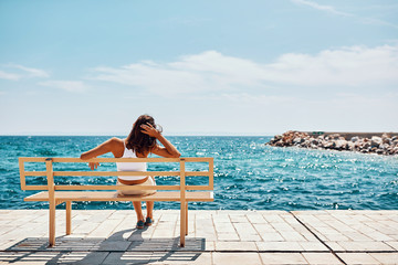 woman watching the sea sitting on a bench and relax.