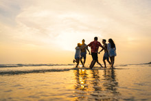 A Group Of Male And Female Friends Who Play Fun On The Sea Beach Amid The Sunset.