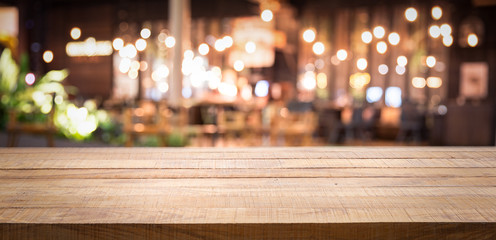 Wall Mural - Empty wood table top and blur of night pub or restaurant background/selective focus .For montage product display