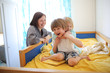 © natalialeb - Siblings hugs with their mother on children's bed