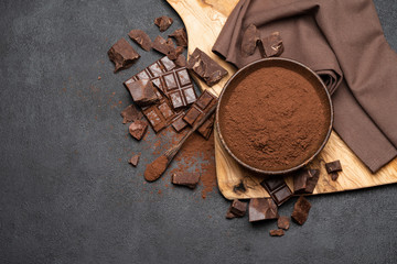 Wall Mural - Dark Chocolate chunks and cocoa powder in wooden bowl on dark concrete background