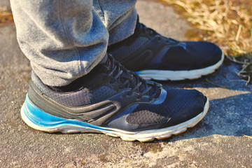 Legs in gray sweatpants and black running shoes sneakers with white and blue soles on the asphalt concept for healthy and active sport lifestyles