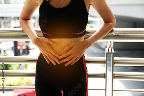 Fotomural Female athletes, abdominal pain, menstrual period during exercise on walking street in the city