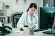 © PR Image Factory - attractive concentrated asian female doctor writing prescription on special form. beautiful japanese woman nurse in white coat and stethoscope sitting at desk make note education of medical news.