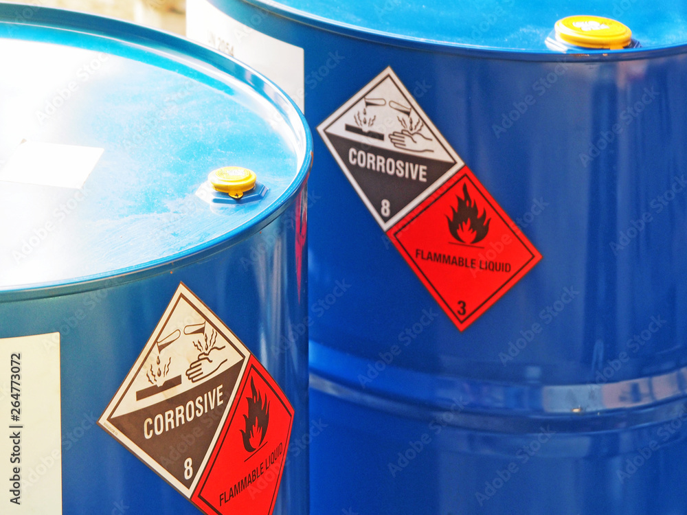 the close-up shot of blue color hazardous dangerous chemical barrels ,have warning labels of corrosive & flammable liquid in daylight on daytime. - obrazy, fototapety, plakaty 