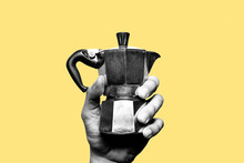 Making Italian Coffee. Hand Holding An Old, Vintage Italian Coffee Maker In Black And White. Isolated. Yellow Background