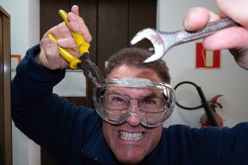 angry young electrician fixing a breakdown with tools in the hands