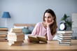 © BestForYou - Beautiful smiling female student reads books at home.