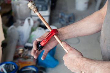 Wall Mural - Closeup worker plumber master measures copper pipes with roulette tape, cut pipe with cutter. Concept installation, changing pipeline, repair, leakage, breaking sewage