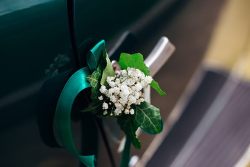 bouquet of lily of the valley with green ribbon on the retro car