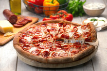 Whole Pepperoni Pizza Pie With A Lifted Slice Of Stringy Cheesy, On Wooden Table With Ingredients