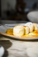 Wall Mural - Cottage cheese pancakes with orange jam on white plate, marble table, at restaurant. Natural light and shadow food photography concept