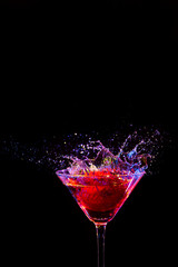 Strawberry with Water Droplets of Colorful Liquid in Wine Glass. Isolated Over Black Background.