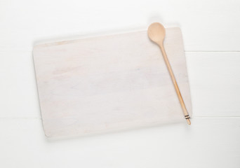 Wall Mural - Empty white cutting board with wooden cooking spoon on white wooden table background
