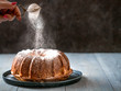 © fascinadora - Woman's hand sprinkling icing sugar over fresh muffin cake. Powder sugar falls on fresh perfect muffin cake. Copy space for text. Ideas and recipes for breakfast or dessert