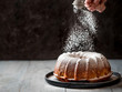 Woman's hand sprinkling icing sugar over fresh muffin cake. Powder sugar falls on fresh perfect muffin cake. Copy space for text. Ideas and recipes for breakfast or dessert