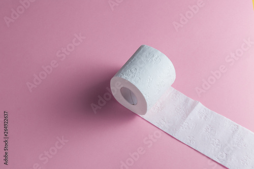 Fotomural a roll of toilet paper isolated on the pink background, top view photo