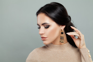 Gorgeous brunette woman with makeup, long hair and jewelry earrings portrait