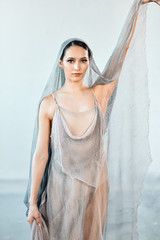 Wall Mural - Portrait of professional ballet dancer in flowing fabric dress and head covered with airy voile posing after the performance. Art concept.