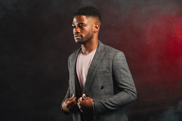 Portrait of handsome self-confident well-groomed imposing man in blazer suit, corporative manager or leader of IT company posing isolated over dark red smoky background