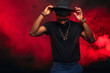 © alfa27 - Portrait of single isolated young african hipster guy dancing in trendy hat and black t-shirt in nightclub over red smoky background