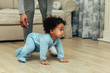 Side view of cute baby boy crawling on floor at home