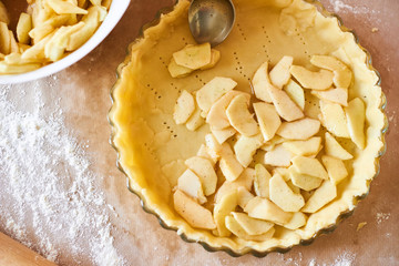 Home baking of holidays classic sweet pies. Woman hands fixing pastry dough in a tray and pumpkin pie ingredients. Preparing traditional desserts