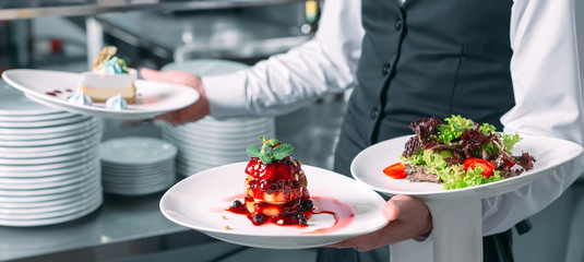 Waiter serving in motion on duty in restaurant. The waiter carries dishes