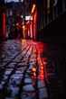 Red ligths of a famous red light distict in Amsterdam, Netherlands. Reflection of neon lighting of showcase windows over wet pavement. European capital of legalized prostitution and marijuana.