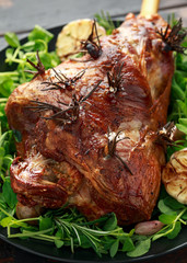 Roast Lamb leg with rosemary and garlic. on black plate, wooden table