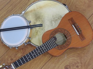 Wall Mural - Three Brazilian musical instruments: cavaquinho, pandeiro (tambourine) and tamborim with drumstick on a wooden surface. The instruments are widely used to accompany samba, a popular Brazilian rhythm.