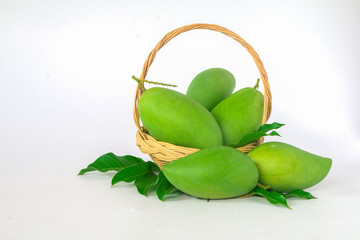 green mangos in a basket on a white background