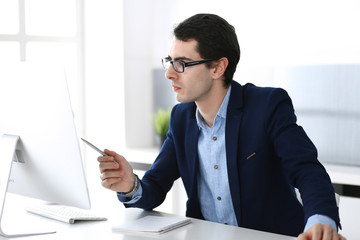 Businessman working with computer in modern office. Headshot of male entrepreneur or company manager at workplace. Business concept