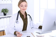 © rogerphoto - Young woman doctor at work in hospital looking at desktop pc monitor. Physician controls medication history records and exam results. Medicine and healthcare concept