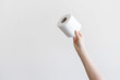 Woman hand holding toilet paper on gray background