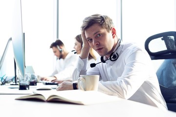 Wall Mural - Worried or tired business man with headset working on computer in office.