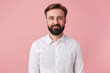 Portrait of young calm smiling handsome bearded man, wearing a white shirt. Looking at the camera isolated over pink background.