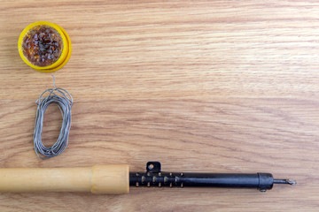 soldering iron and solder on a wooden table, tin wire and rosin