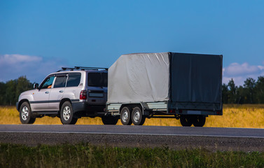 Wall Mural - Car with a Trailer moves on a country road