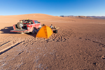 Two adventurers people at its campsite in Atacama Desert vast dry extension, the driest area of this amazing desert. An old dry ground with an infinite horizon for having a great outdoors adventure
