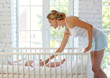 © dinaphoto - Portrait of mother and newborn baby at the white children's bed.