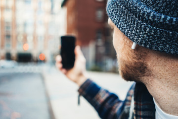 Wall Mural - Man walking on a sidewalk on the city street using mobile phone and taking selfie photos