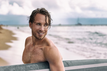 Sexy surfer surfing man with surfboard. Handsome young male athlete holding surf board with wet hair on summer beach sport holiday. Sports travel destination. Surfing lifestyle.