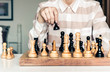 © Inna - Wooden chess pieces on a chessboard, chess game woman player makes a move.