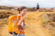 © Maridav - Happy young Asian hiker girl hiking with friend in mountain nature trail wearing orange backpack smiling looking back enjoying travel holiday in summer. Adventure wanderlust lifestyle. Healthy woman.